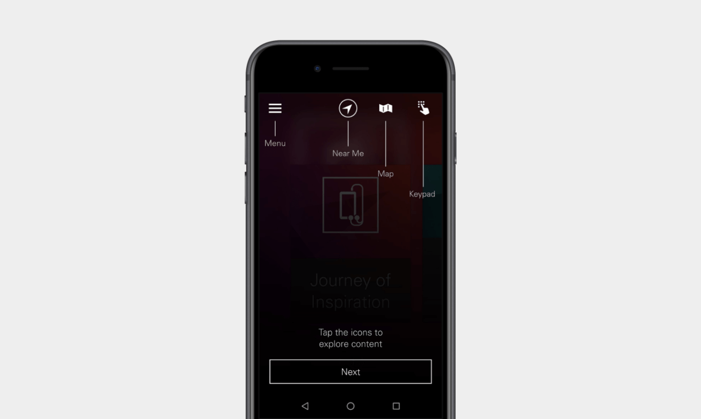 Small icons at the top of a mobile phone screen are labeled, from left to right, Menu, Near Me, Map, and Keypad. At the bottom of the phone's screen is a rectangular box with the word "Next" inside. Above the box is the text, "Tap the icons to explore content."